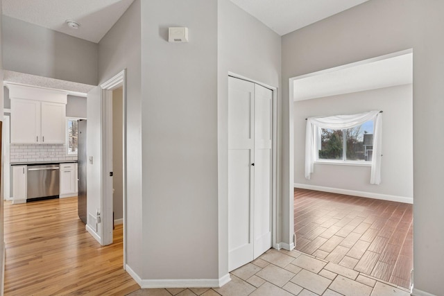 corridor with baseboards and light wood-style floors