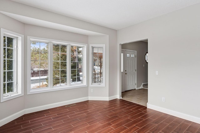 empty room with visible vents, baseboards, and wood finish floors