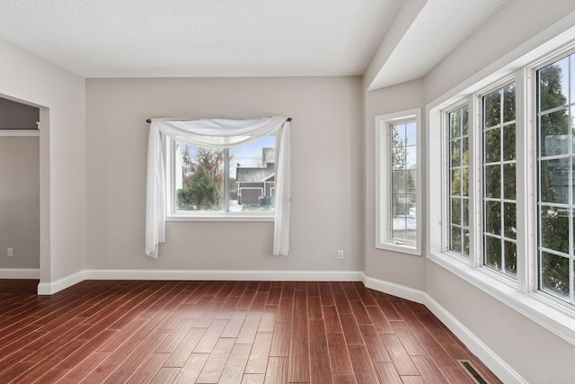 unfurnished room with dark wood finished floors, visible vents, baseboards, and a wealth of natural light