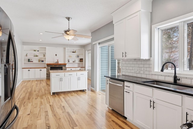 kitchen with a sink, white cabinets, light wood-style floors, stainless steel dishwasher, and fridge with ice dispenser