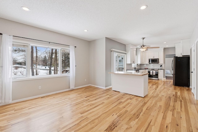 kitchen with white cabinetry, light wood-style floors, tasteful backsplash, and appliances with stainless steel finishes