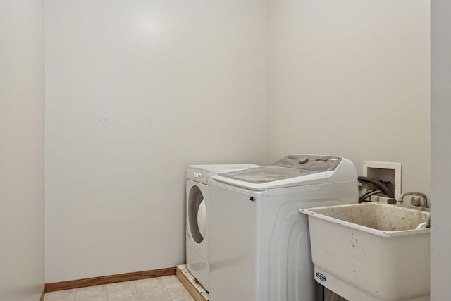 laundry area with laundry area, separate washer and dryer, baseboards, and a sink