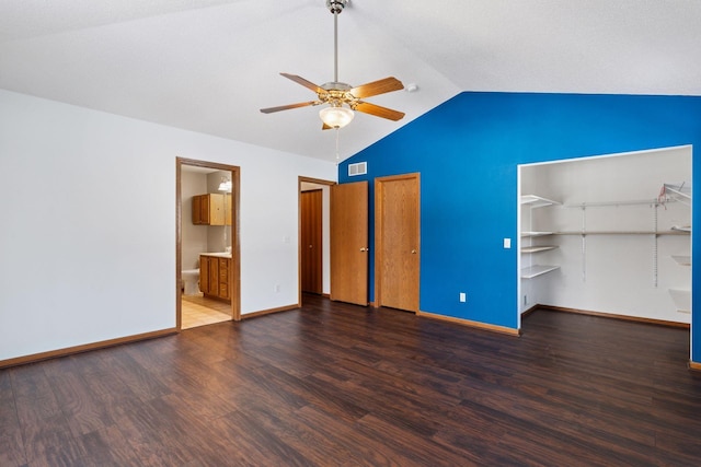 unfurnished bedroom featuring visible vents, two closets, baseboards, vaulted ceiling, and wood finished floors