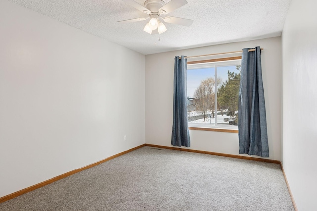 carpeted spare room with ceiling fan, a textured ceiling, and baseboards