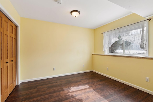 interior space featuring dark wood finished floors, baseboards, and a closet