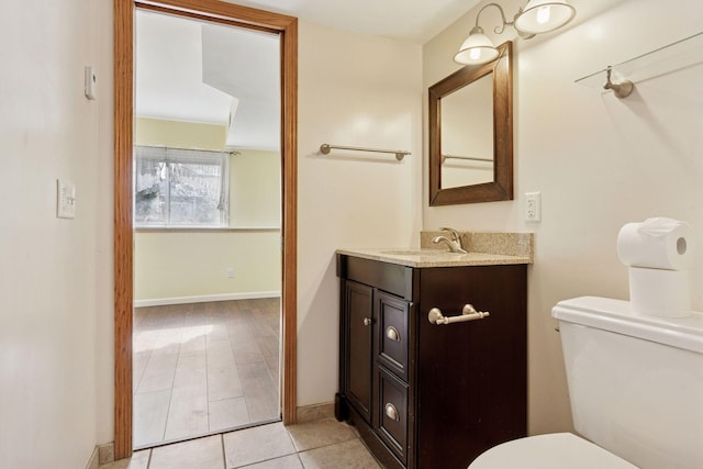 half bath featuring baseboards, toilet, vanity, and tile patterned flooring