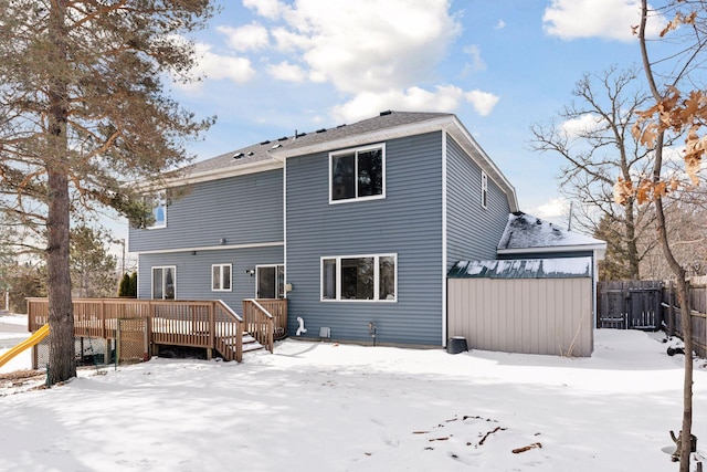 snow covered house featuring a wooden deck and fence