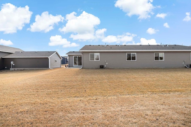 rear view of house with central AC unit and a lawn