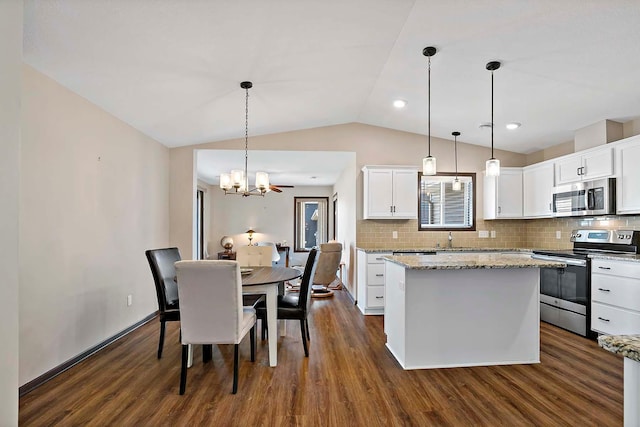 kitchen with dark wood-style flooring, stainless steel appliances, lofted ceiling, tasteful backsplash, and a kitchen island