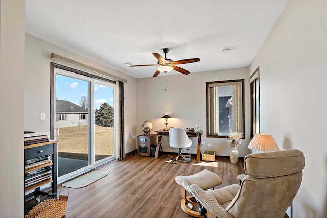 living area featuring a ceiling fan, baseboards, and wood finished floors