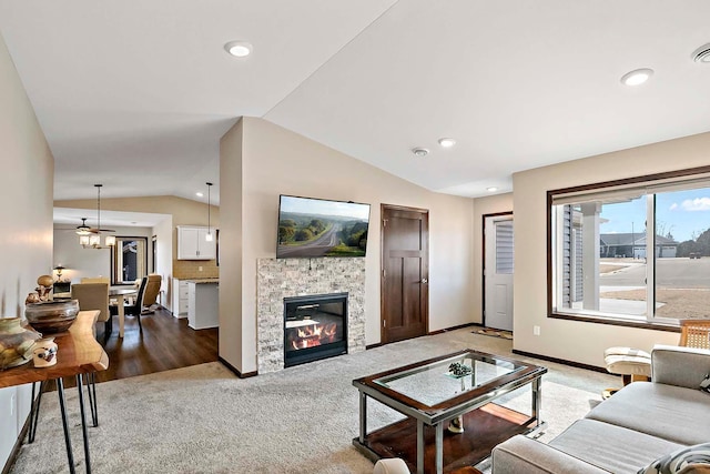 living room featuring recessed lighting, carpet, vaulted ceiling, baseboards, and a glass covered fireplace