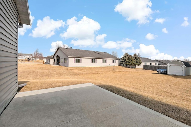 view of yard featuring a detached garage, an outdoor structure, a residential view, and a patio