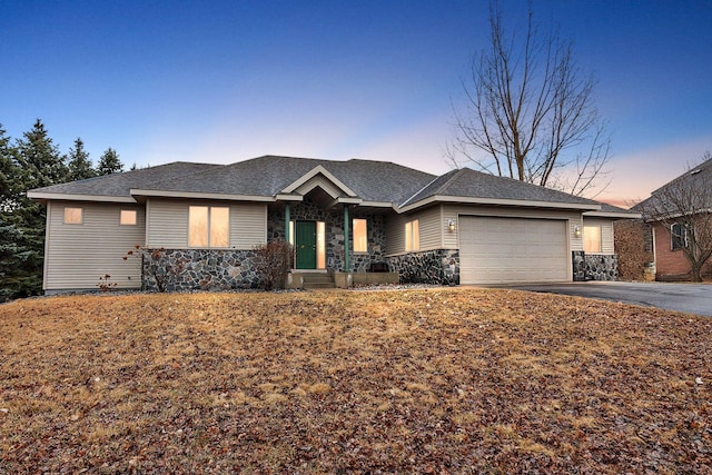 single story home featuring a garage, stone siding, and driveway