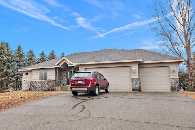 ranch-style house featuring stone siding, driveway, a shingled roof, and an attached garage