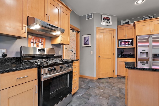 kitchen with dark stone countertops, baseboards, visible vents, stainless steel appliances, and under cabinet range hood