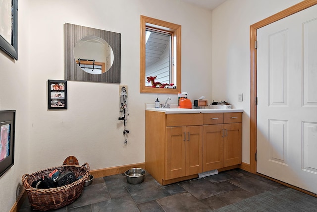 bathroom featuring vanity, stone finish floor, and baseboards