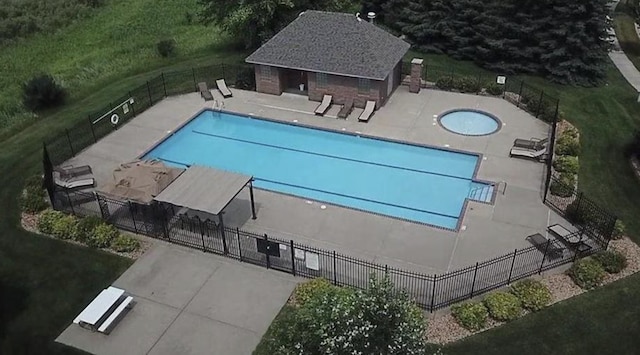 community pool with a patio, fence, and an outbuilding