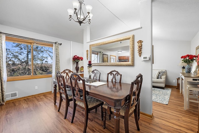 dining room with plenty of natural light, wood finished floors, visible vents, and an inviting chandelier