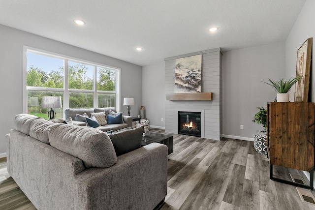 living area featuring a fireplace, recessed lighting, visible vents, wood finished floors, and baseboards