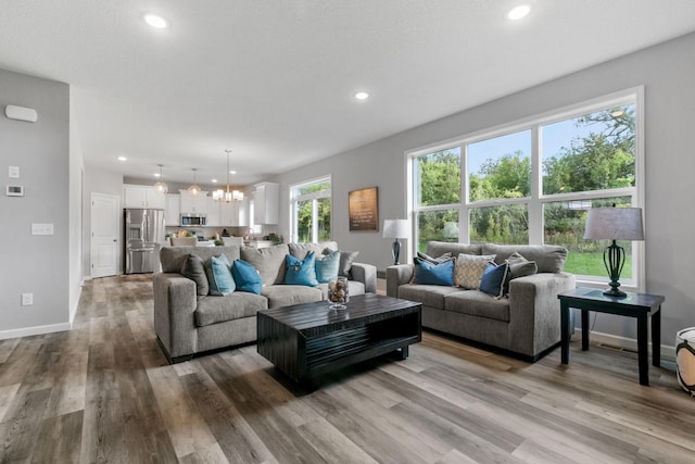 living room with a chandelier, recessed lighting, baseboards, and wood finished floors