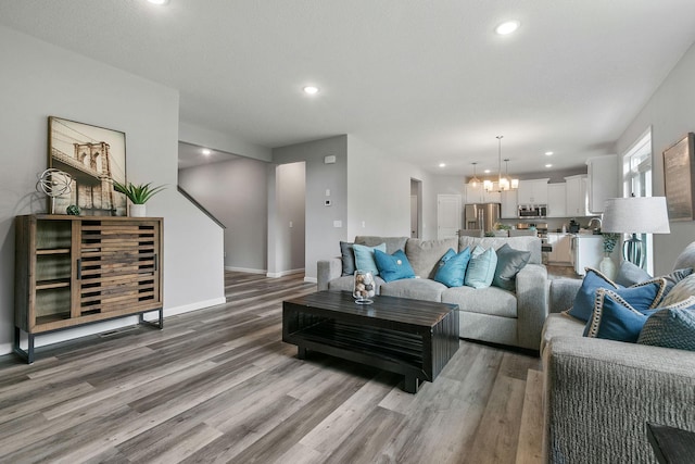 living room with recessed lighting, a notable chandelier, light wood-style flooring, and baseboards