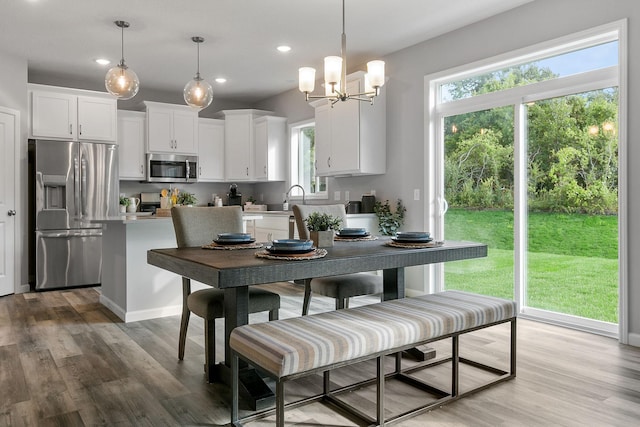 dining room with light wood-type flooring, a healthy amount of sunlight, and recessed lighting