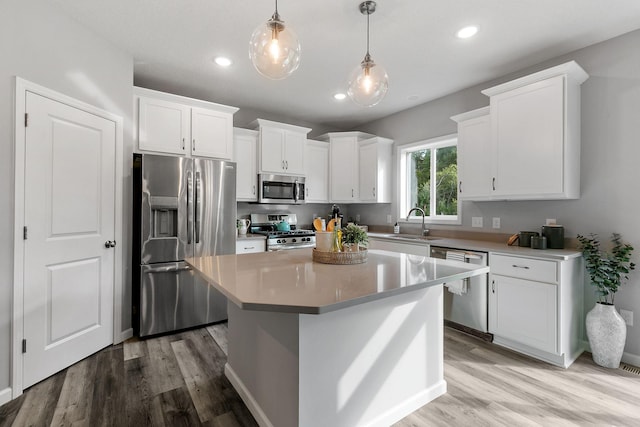 kitchen with a kitchen island, white cabinetry, stainless steel appliances, and a sink