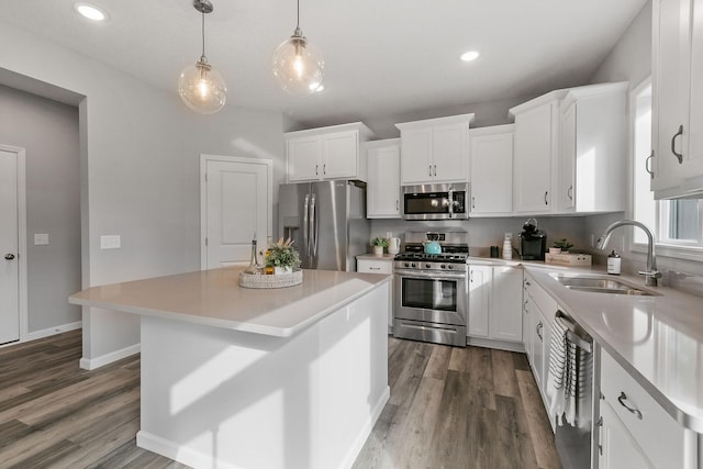 kitchen featuring appliances with stainless steel finishes, light countertops, a sink, and wood finished floors