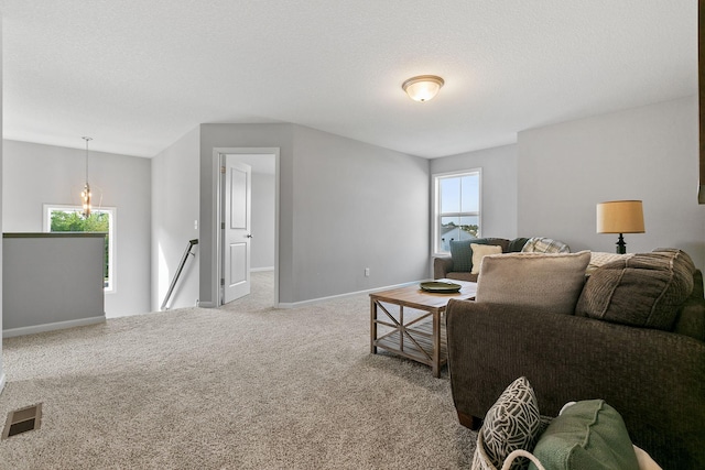 living area featuring a textured ceiling, carpet floors, visible vents, and baseboards