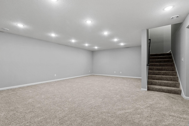 basement featuring carpet floors, recessed lighting, and stairway