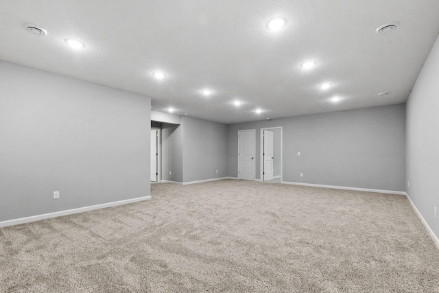 unfurnished room featuring light carpet, a textured ceiling, recessed lighting, and baseboards