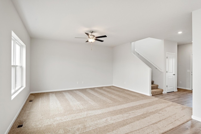 empty room featuring baseboards, visible vents, stairway, and ceiling fan