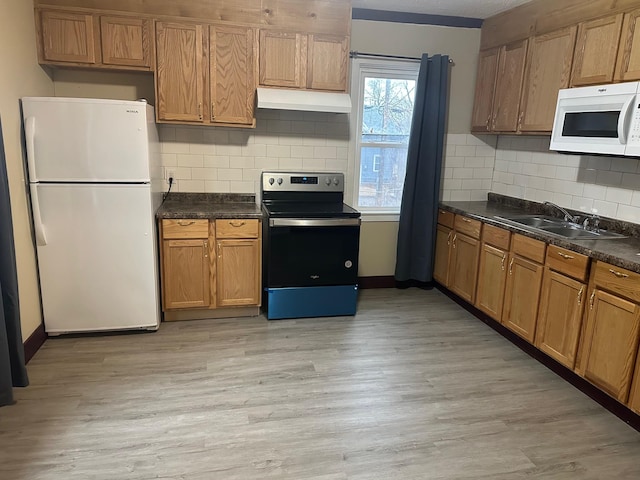 kitchen with dark countertops, light wood-style floors, a sink, white appliances, and under cabinet range hood