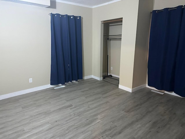 unfurnished bedroom with ornamental molding, baseboards, and wood finished floors