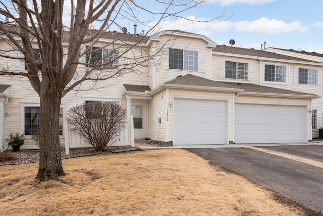 townhome / multi-family property featuring driveway, an attached garage, and a shingled roof