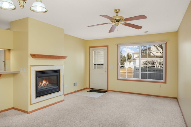 unfurnished living room featuring carpet floors, a fireplace, baseboards, and a ceiling fan