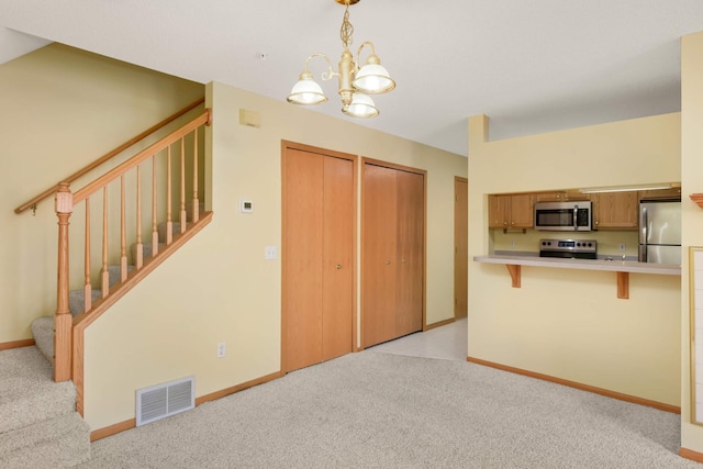 kitchen featuring stainless steel appliances, light countertops, visible vents, light carpet, and a kitchen bar