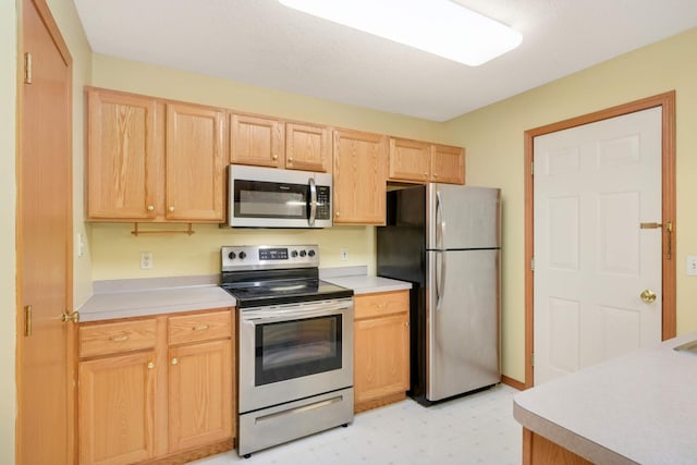 kitchen with light floors, light brown cabinets, appliances with stainless steel finishes, and light countertops