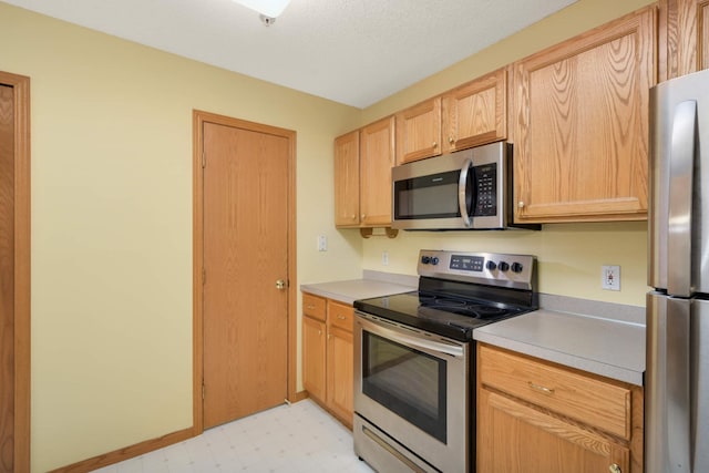 kitchen with stainless steel appliances, light brown cabinets, light countertops, and light floors