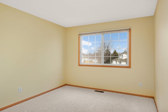 carpeted spare room with visible vents and baseboards