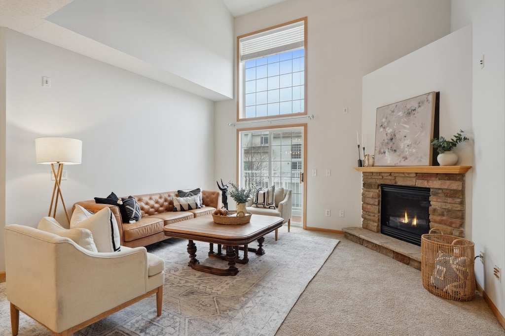 living area with carpet, a high ceiling, a fireplace, and baseboards