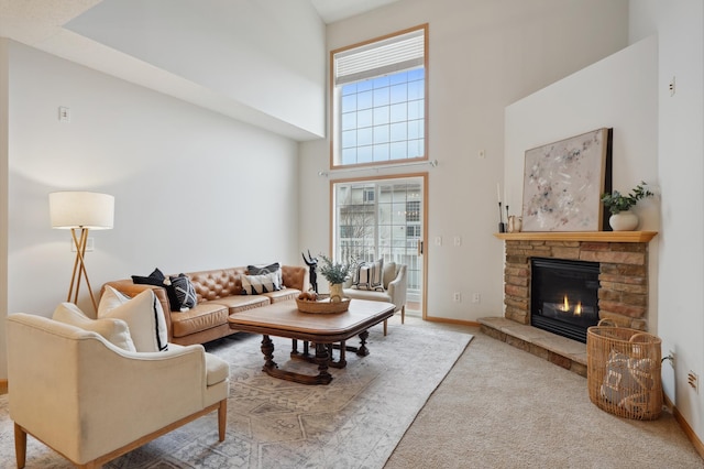 living area with carpet, a high ceiling, a fireplace, and baseboards