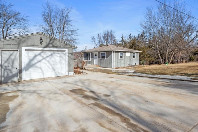 view of front of house with a detached garage, an outbuilding, board and batten siding, and concrete driveway