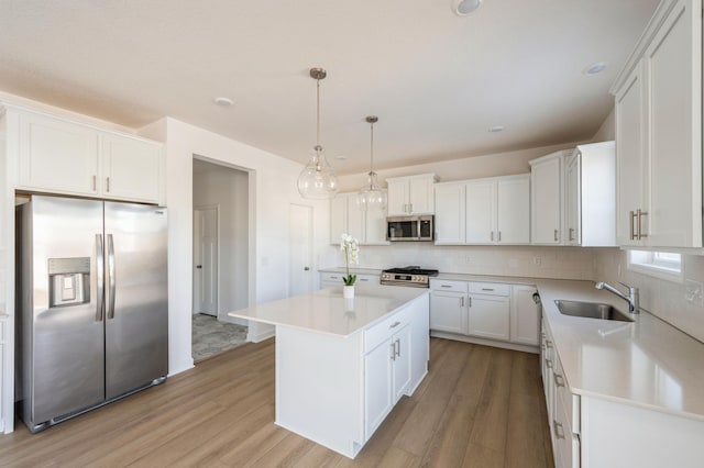 kitchen with appliances with stainless steel finishes, a center island, light countertops, and a sink