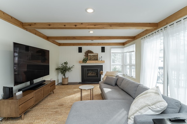 living room featuring beam ceiling, a fireplace with flush hearth, and recessed lighting