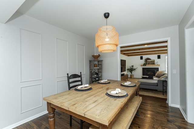 dining room with dark wood-type flooring, beamed ceiling, a fireplace, and baseboards