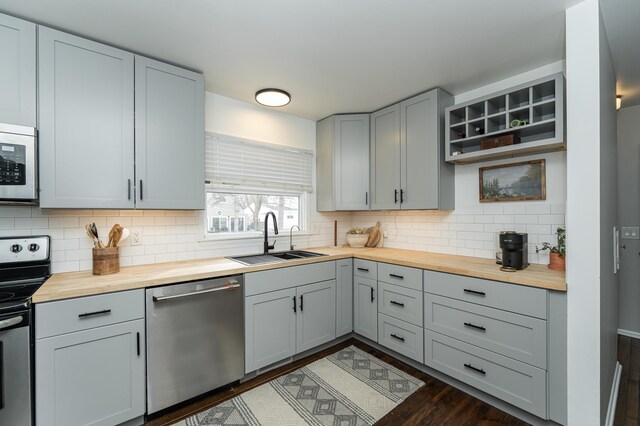 kitchen with a sink, stainless steel appliances, backsplash, and butcher block countertops