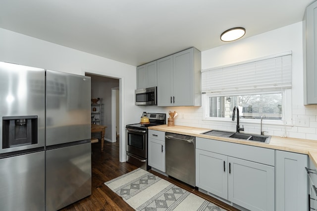 kitchen featuring tasteful backsplash, wooden counters, stainless steel appliances, and a sink