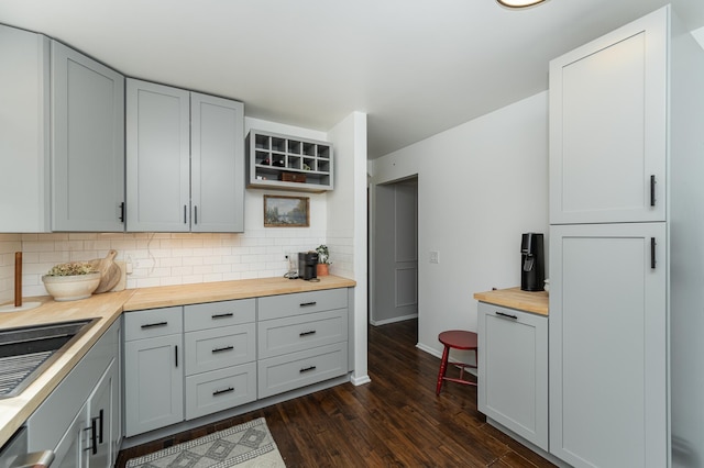 kitchen with decorative backsplash, butcher block countertops, dark wood-style floors, and gray cabinetry