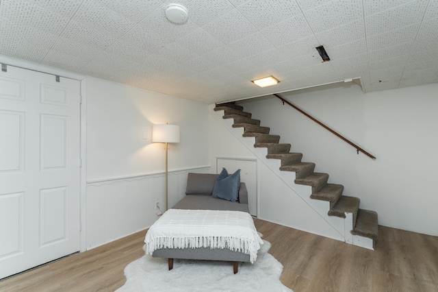 living area with a wainscoted wall, wood finished floors, and stairway